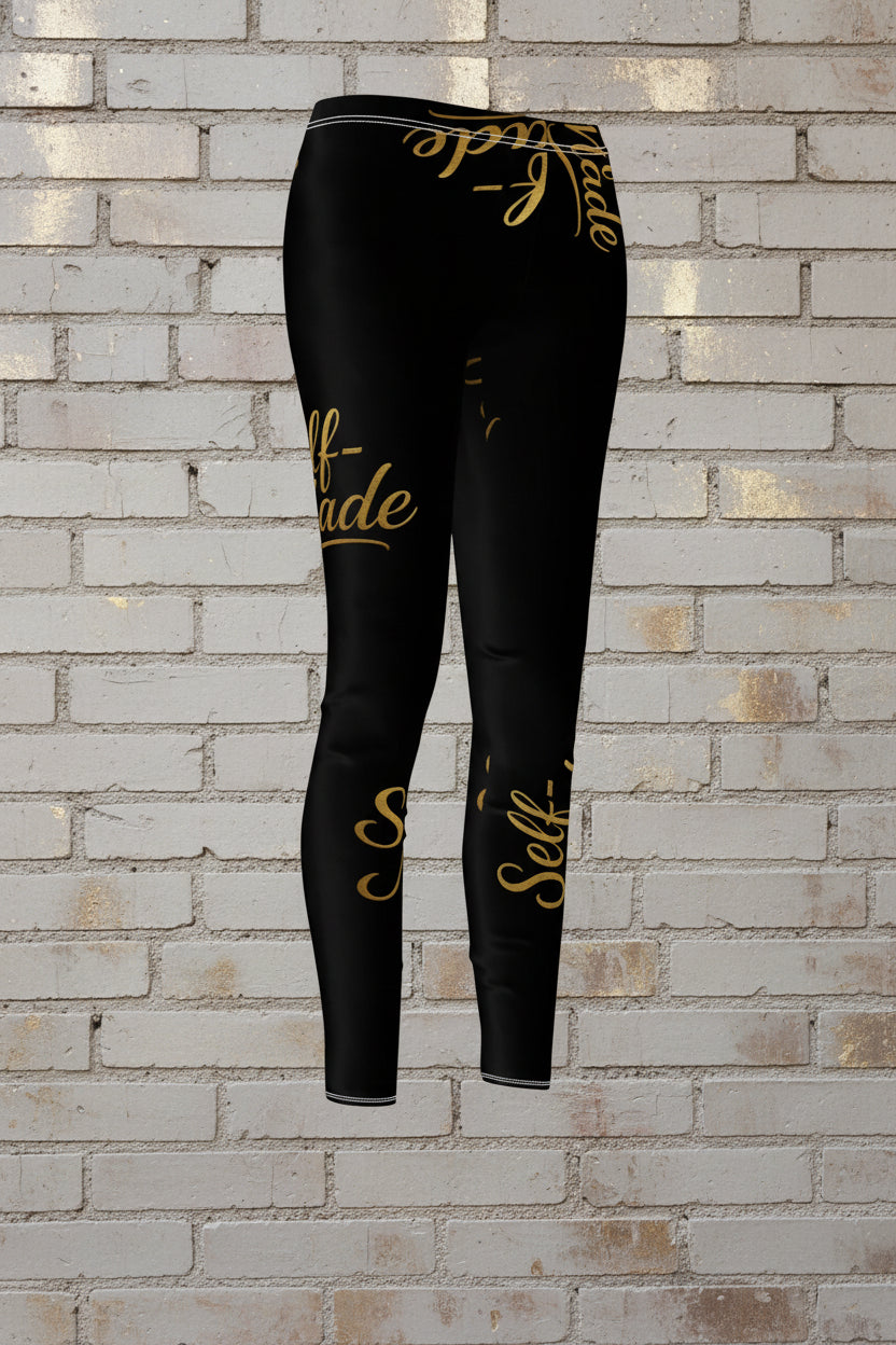 Women's black activewear leggings with metallic gold Self Made script on a brick background.