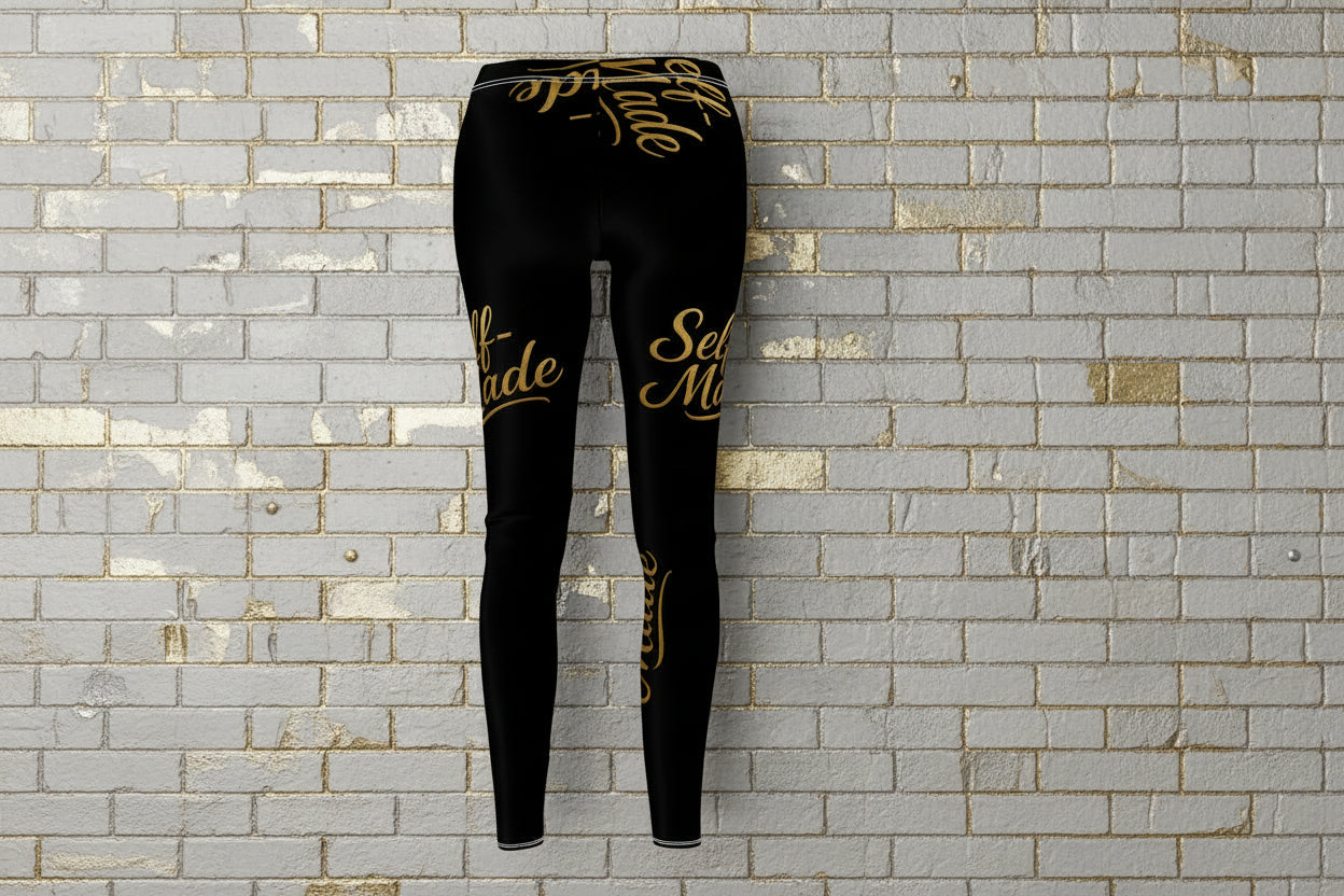 Back view of Self Made gold script black leggings on a grey brick background, showcasing women's compression activewear.