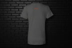 Back view of the grey Unbothered Vibe women's graphic v-neck tee featuring a small orange logo on a dark brick background.