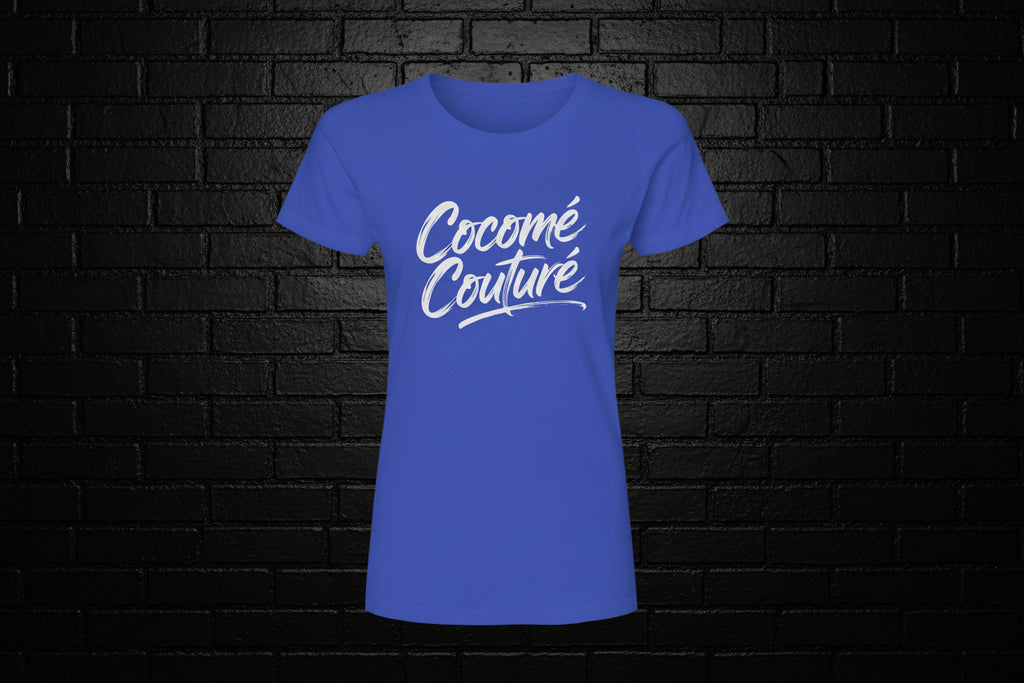 Cocome Couture premium royal blue cotton tee with white script logo on a black brick background.