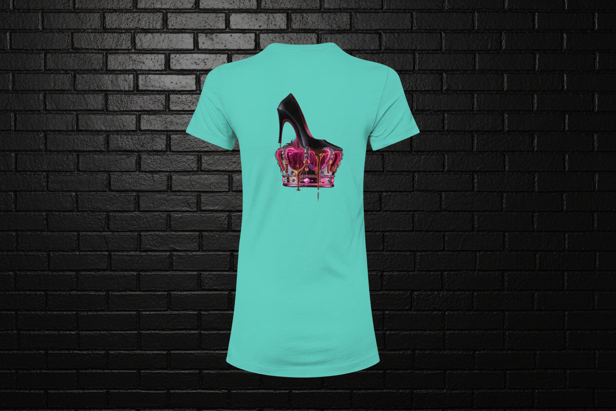 Royal Rebellion Graphic Tee in teal featuring a black stiletto on a molten pink and gold crown, shown against a brick wall.
