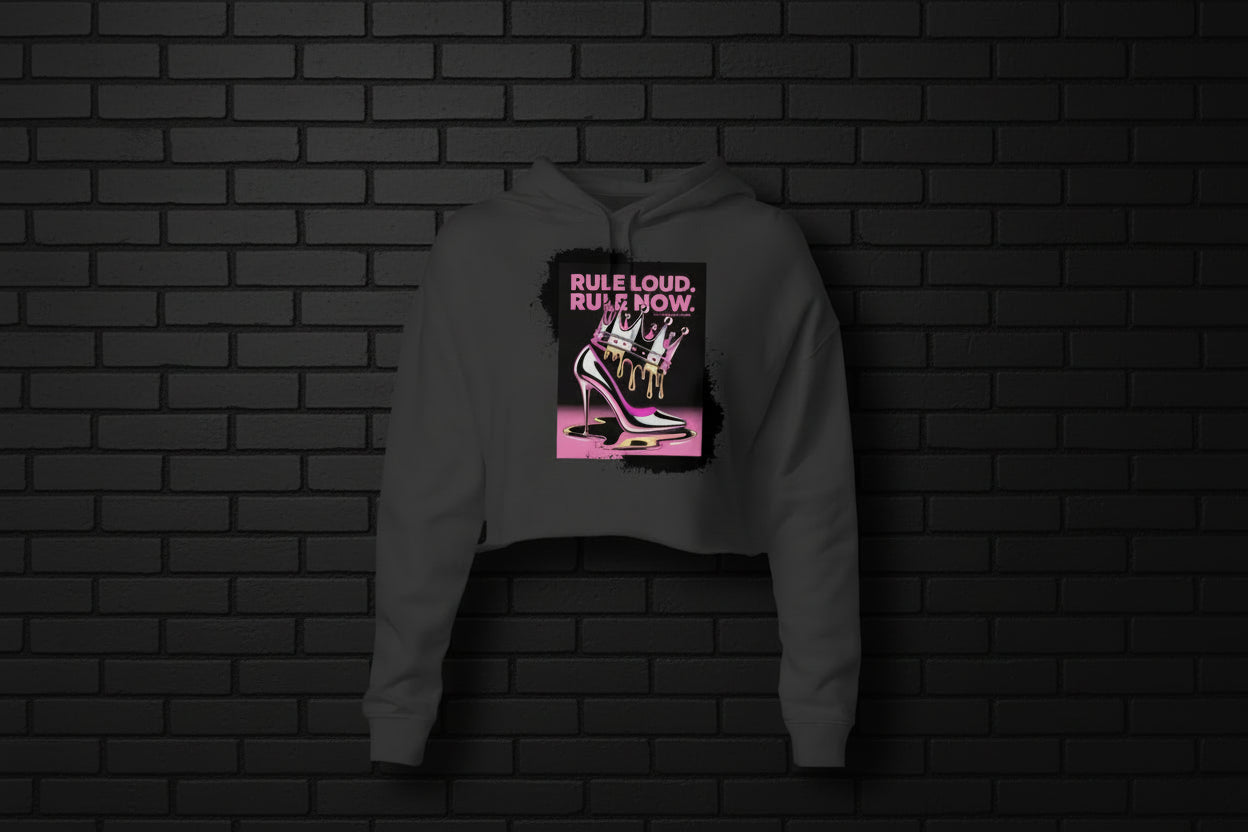Rule Loud Women's Crop Hoodie in Charcoal with crown and stiletto heel graphic on a black brick background.