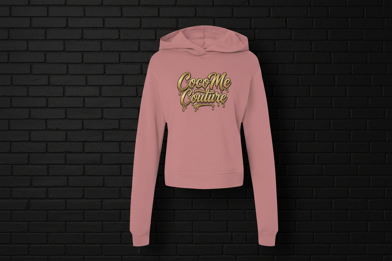 Mauve pink fleece Kiss My Couture luxe streetwear hoodie with gold drip logo on a black brick background.