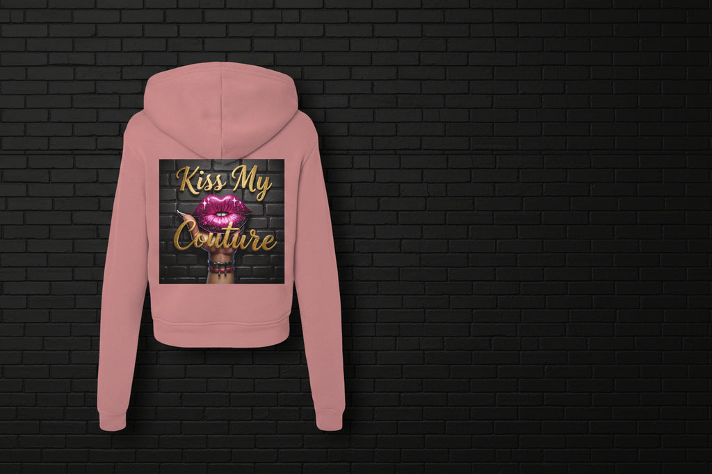 Back view of mauve Kiss My Couture Luxe Streetwear hoodie with pink lips graphic against a black brick wall background.