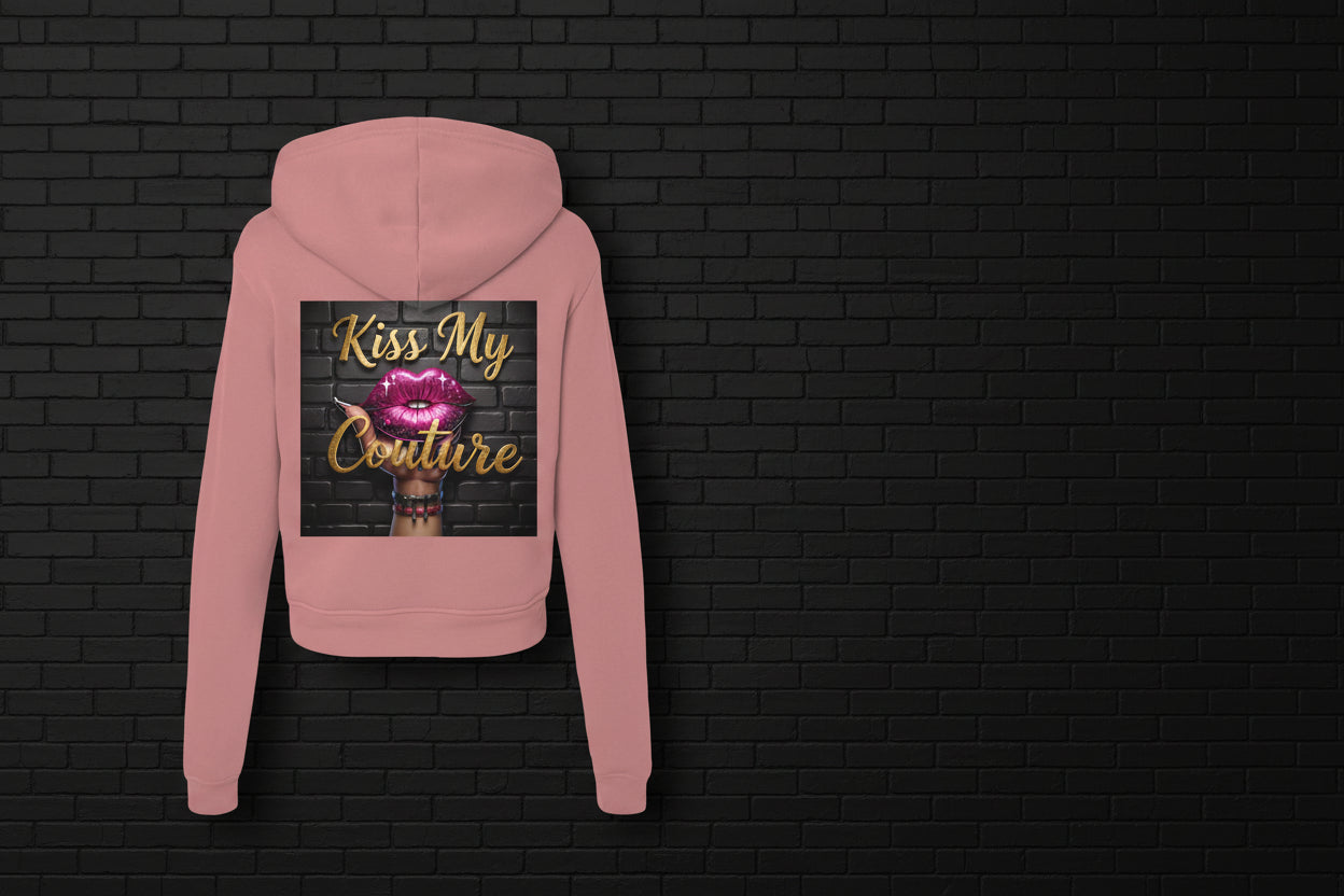 Back view of mauve Kiss My Couture Luxe Streetwear hoodie with pink lips graphic against a black brick wall background.