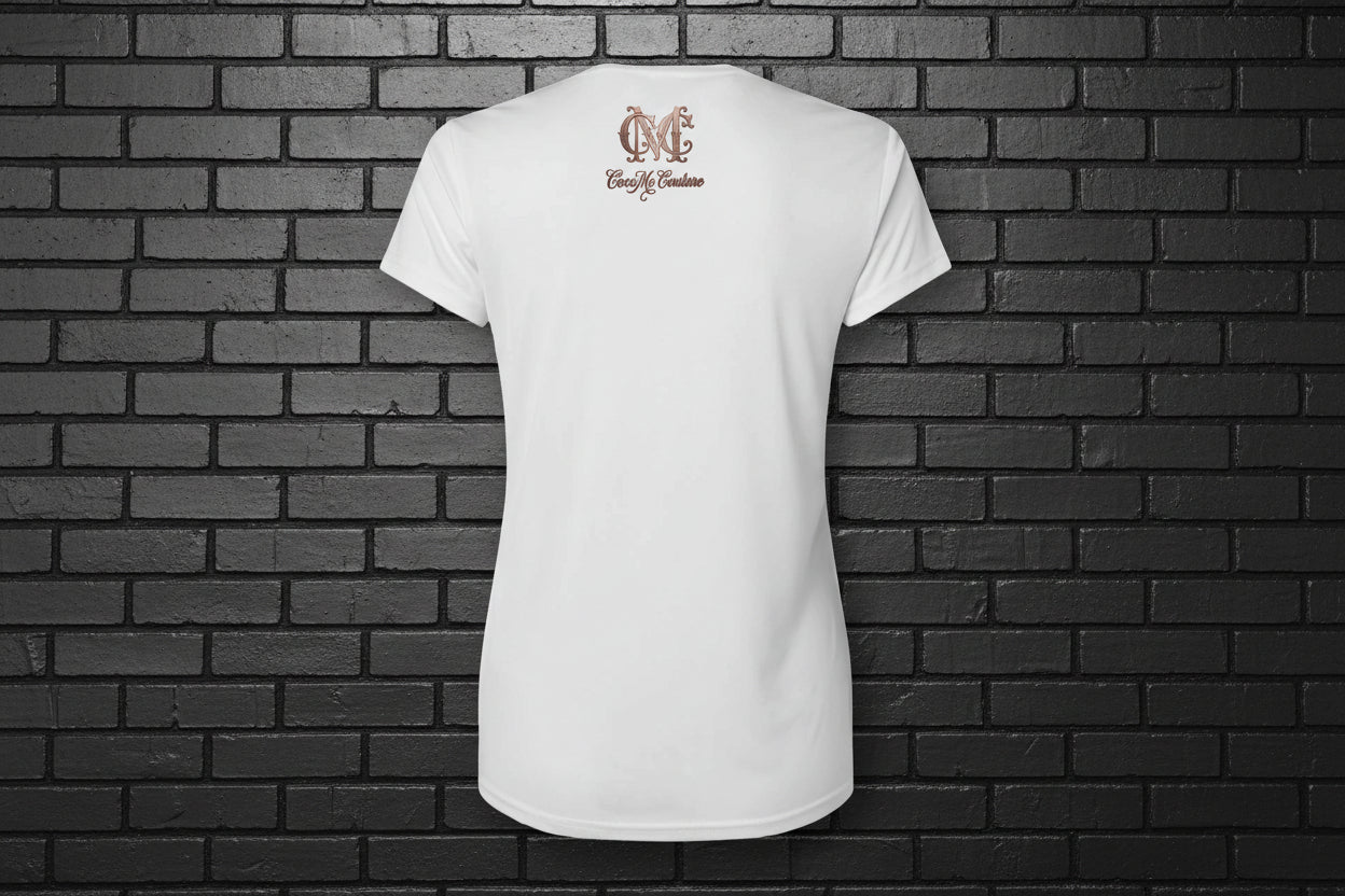 Back view of the Soft but Dangerous Performance Tee in white with Cocome Couture logo on a black brick background.