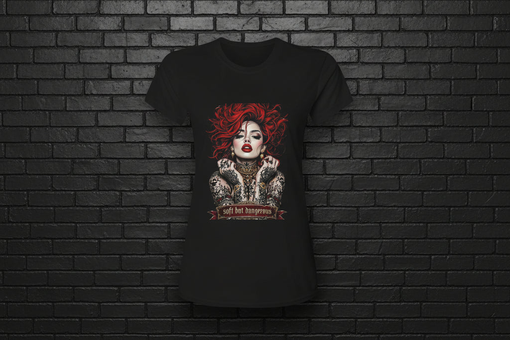 Women's black Soft but Dangerous Performance Tee with red-haired gothic graphic on a brick background.