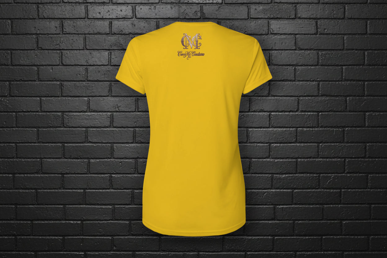 Back view of Soft but Dangerous Women's Activewear Performance Tee in gold with Cocome Couture logo on black brick.