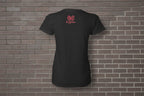 Back view of black cotton women's graphic t-shirt with pink logo on a brick wall background.
