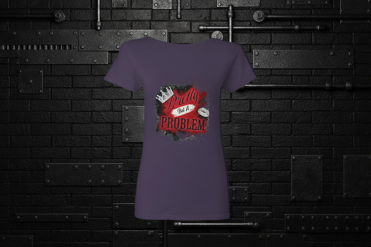 Purple women's cotton graphic tee with Pretty But A Problem crown design against a black industrial brick wall.