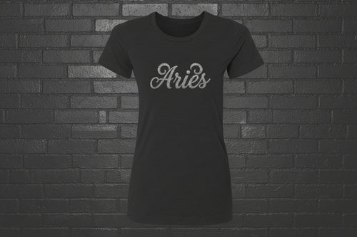 Black heavyweight Aries zodiac shirt with cursive silver text, modern classic fit on a black brick background.