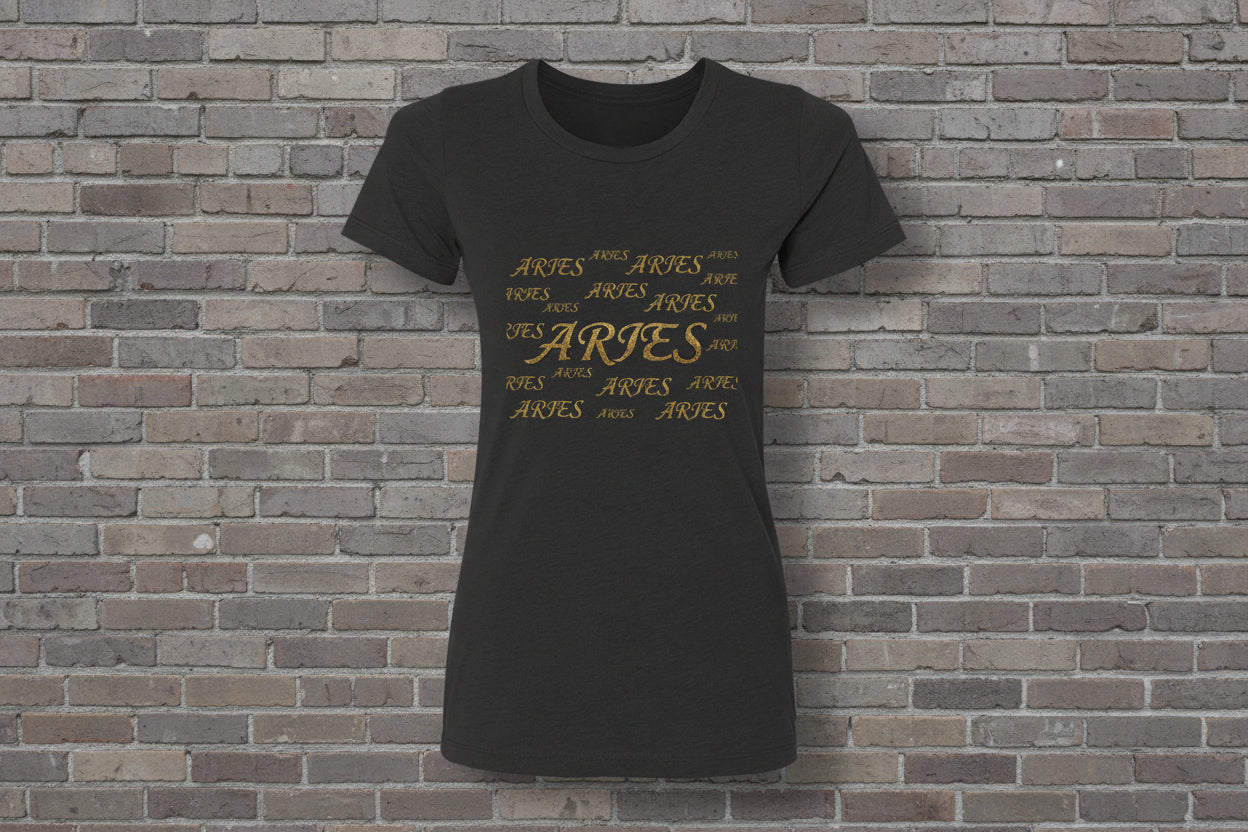 Aries the Ram Premium Tee in black featuring a gold metallic astrology graphic on a brick wall background.