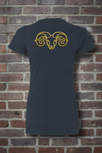 Back view of navy Aries the Ram zodiac graphic tee with a gold ram head design, styled against a brick wall background.