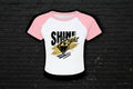 Women's 90s style Y2K raglan baby tee in pink and white micro rib with Shine Bright diamond graphic.