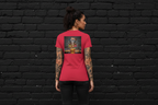 Back view of a woman wearing the red Aries Zodiac graphic t-shirt in heavyweight cotton against a black brick wall.