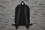 Rear view of Pretty But A Problem laptop backpack showing ergonomic padded straps and mesh back against a brick wall.