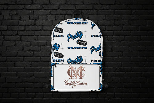White Pretty But A Problem laptop backpack with blue graphic text and Cocome Couture logo against a black brick wall.