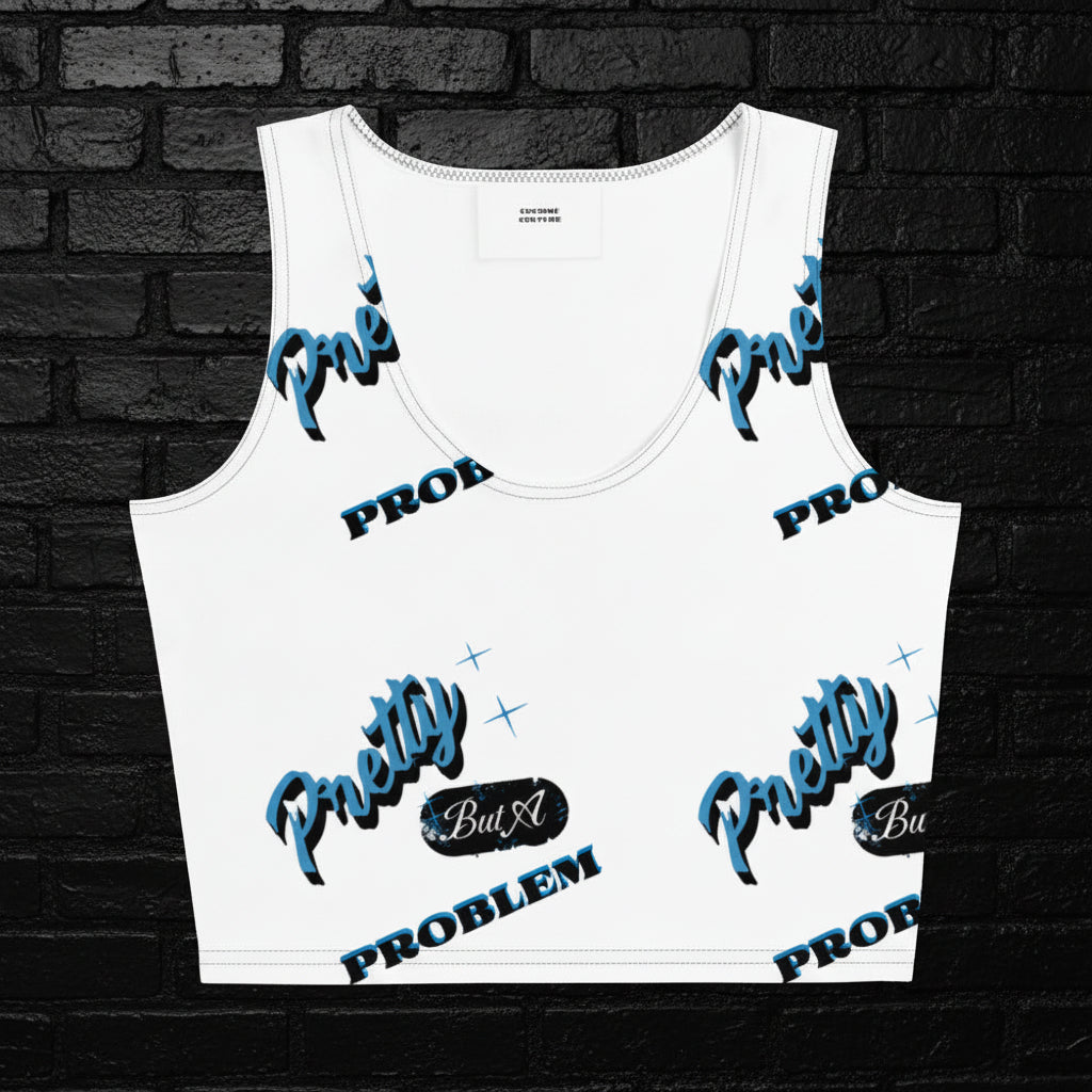 Women's white graphic crop top with blue 'Pretty But A Problem' text pattern and scoop neck on a black brick background.